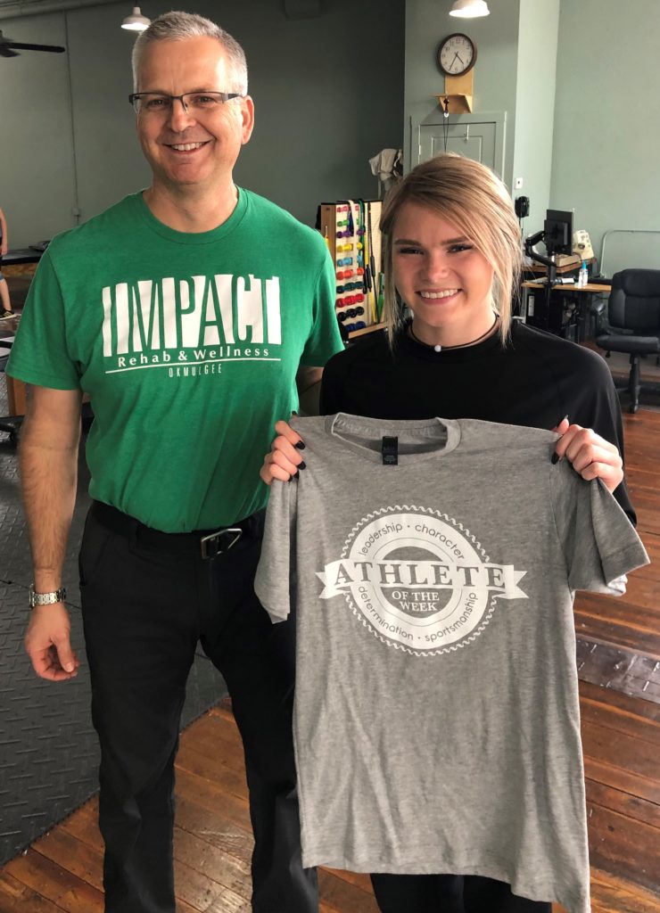 Winner of Impact Athlete of the Week, Bailee Worlow, holds up her shirt with physical therapist, Michael Siegenthaler.