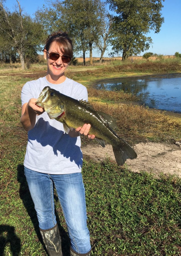 Michelle Johnson, PT, MPT, CFSC holding up a largemouth bass she just caught. She is joining our team at Impact.