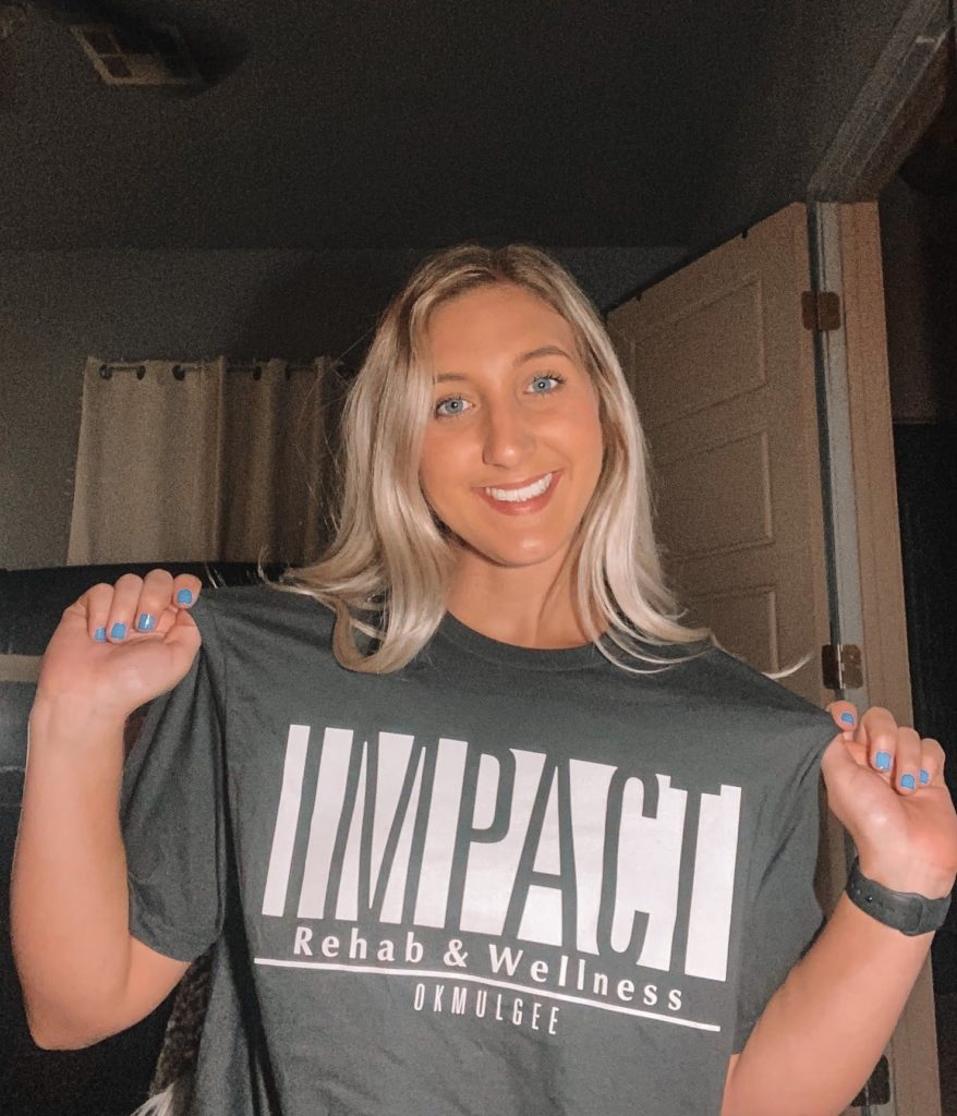 Gabby Tucker, PTA, new employee of Impact Rehab & Wellness, wearing her Impact shirt.